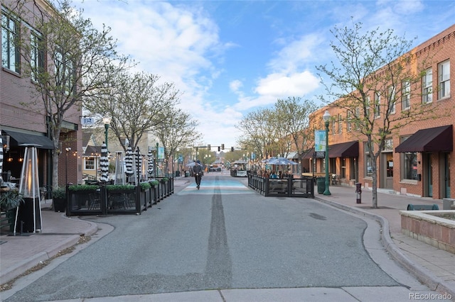 view of street with street lighting, sidewalks, traffic lights, and curbs