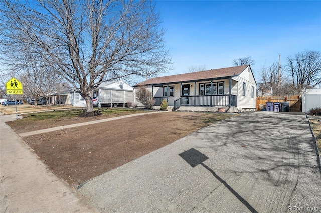 view of front of house featuring covered porch, driveway, and fence