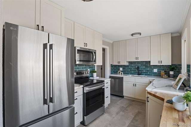 kitchen featuring a sink, backsplash, appliances with stainless steel finishes, and ornamental molding