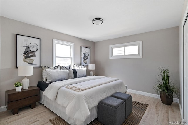 bedroom featuring light wood finished floors, visible vents, and baseboards