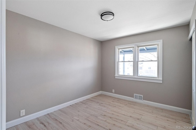 spare room with visible vents, light wood-type flooring, and baseboards