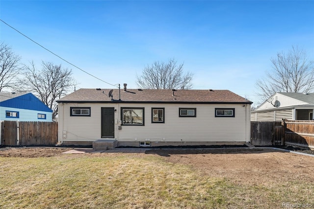 rear view of house with a lawn, entry steps, and fence