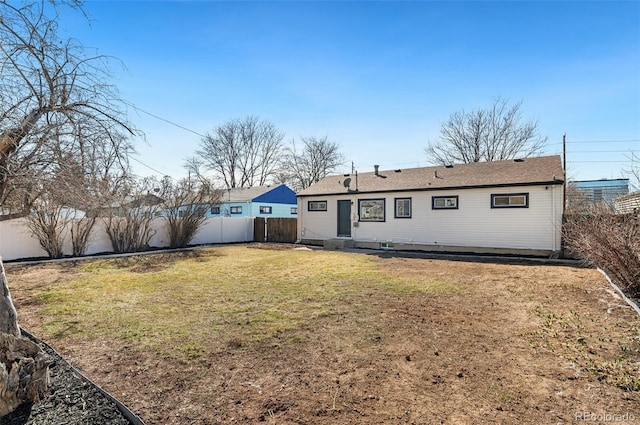 rear view of property featuring a yard and a fenced backyard