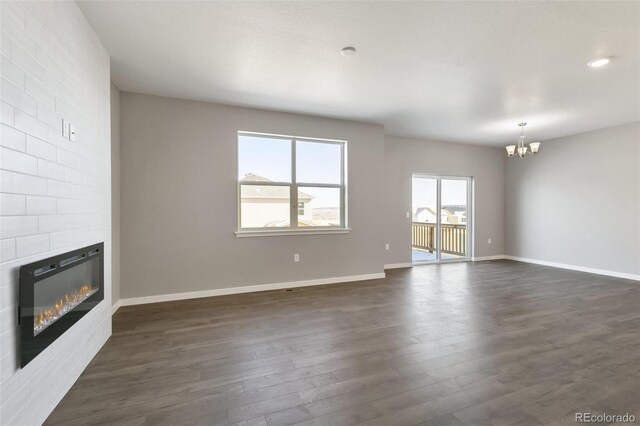 27746 E Byers Pl, Aurora, CO 80018 - unfurnished living room with a chandelier, a large fireplace, dark wood-style flooring, and baseboards