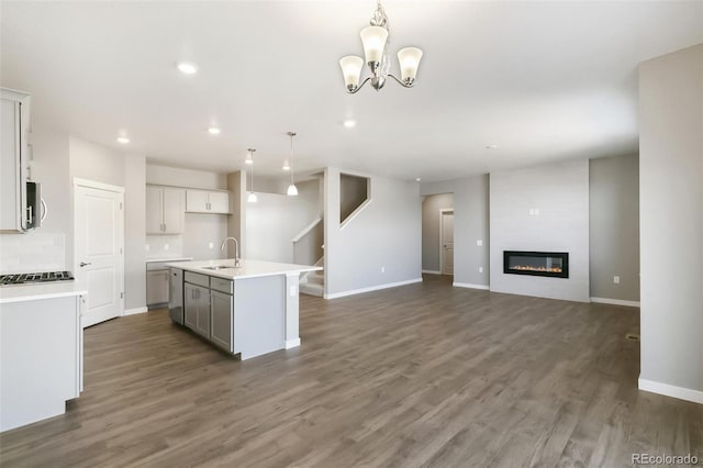 27746 E Byers Pl, Aurora, CO 80018 - kitchen featuring open floor plan, stainless steel microwave, a center island with sink, recessed lighting, and dark wood-type flooring