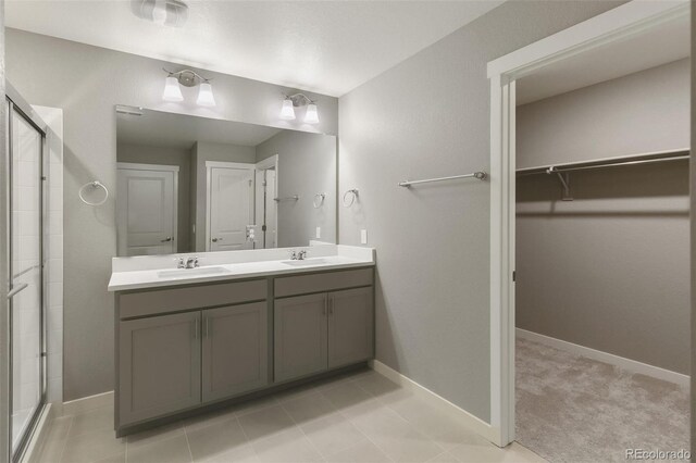 27746 E Byers Pl, Aurora, CO 80018 - full bathroom with a stall shower, a spacious closet, double vanity, and baseboards