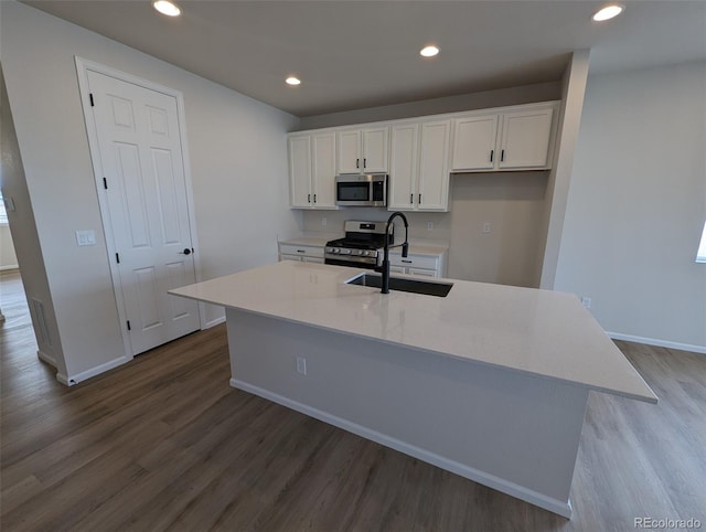 kitchen with a center island with sink, sink, dark hardwood / wood-style floors, appliances with stainless steel finishes, and white cabinetry