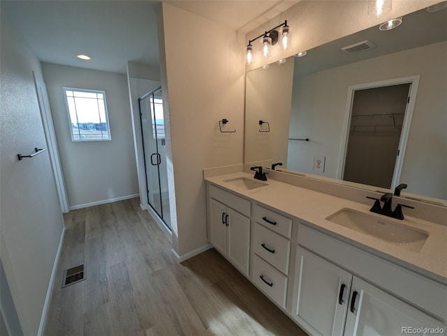 bathroom with wood-type flooring, vanity, and an enclosed shower