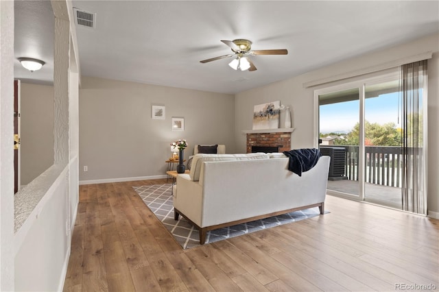 living room featuring ceiling fan, a fireplace, and light hardwood / wood-style floors