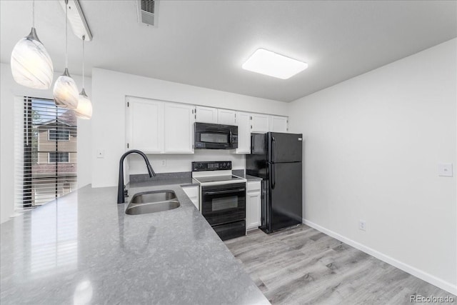 kitchen with visible vents, black appliances, a sink, decorative light fixtures, and white cabinets