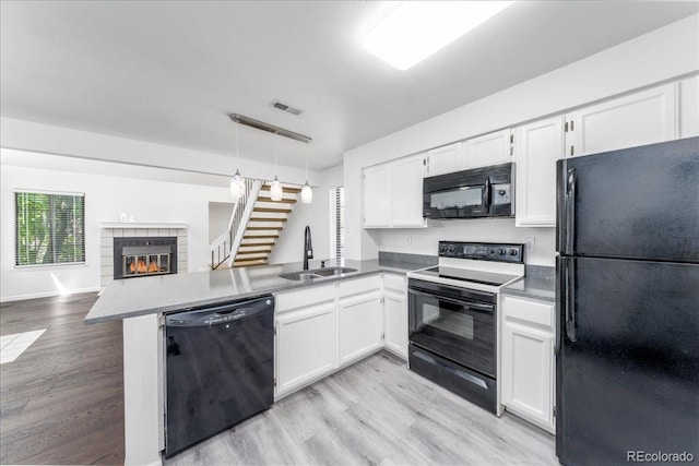 kitchen with visible vents, a peninsula, a sink, black appliances, and open floor plan