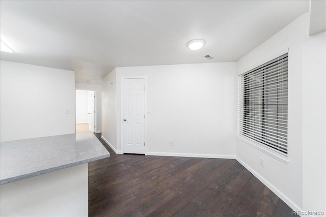 unfurnished room with dark wood-style floors and baseboards