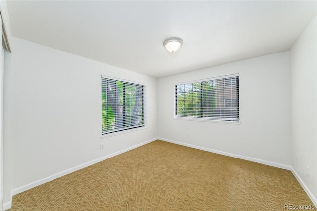 carpeted empty room with baseboards