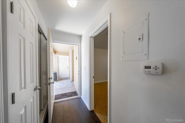 hallway featuring electric panel, baseboards, and dark wood-style flooring