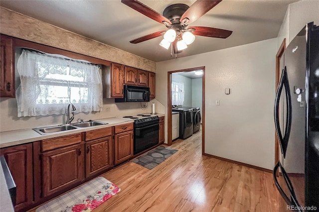 kitchen with a ceiling fan, separate washer and dryer, a sink, light wood finished floors, and black appliances