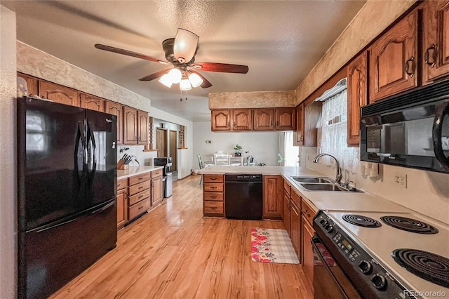 kitchen with a ceiling fan, light wood-type flooring, a sink, black appliances, and a peninsula