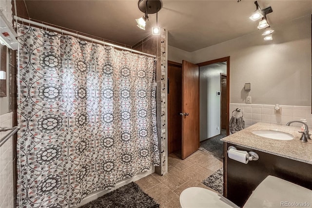 full bathroom with vanity, toilet, a wainscoted wall, tile walls, and curtained shower