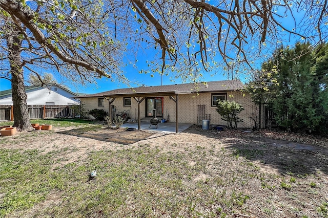 rear view of house with a yard, brick siding, fence, and a patio