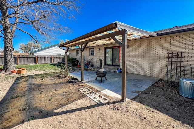 rear view of house featuring a fenced backyard, a fire pit, a patio area, and brick siding