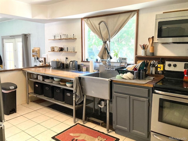 5350 Primrose Ln, Denver, CO 80221 - kitchen with appliances with stainless steel finishes, light tile patterned floors, gray cabinetry, and open shelves