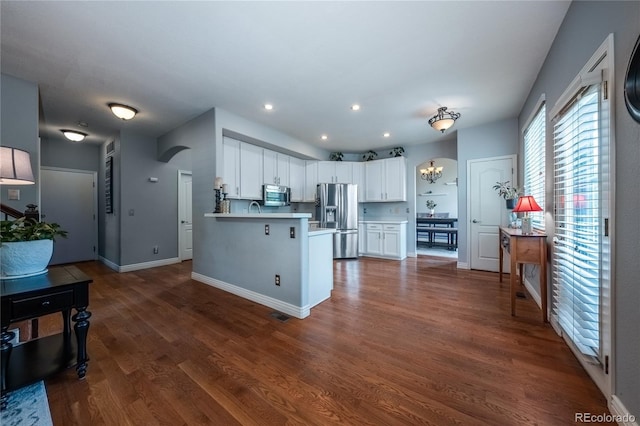 9758 Red Oakes Dr, Highlands Ranch, CO 80126 - kitchen featuring stainless steel appliances, white cabinetry, dark wood-style floors, light countertops, and a peninsula