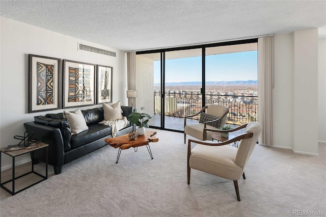 living area featuring a wall of windows, baseboards, visible vents, carpet floors, and a textured ceiling