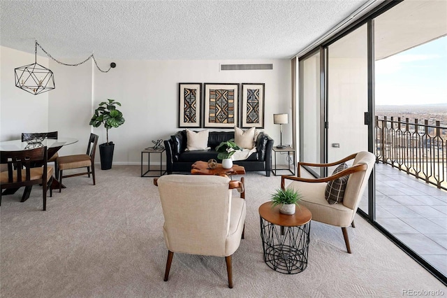 living area with a textured ceiling, carpet, visible vents, tile patterned flooring, and expansive windows