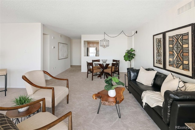 living room with a textured ceiling, visible vents, and light carpet