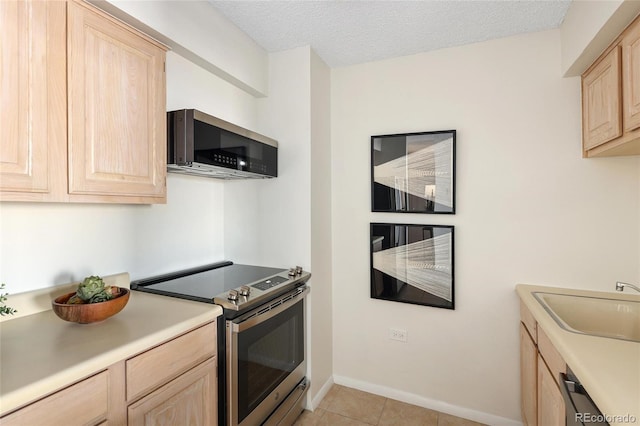 kitchen featuring light brown cabinetry, light countertops, stainless steel appliances, a textured ceiling, and a sink