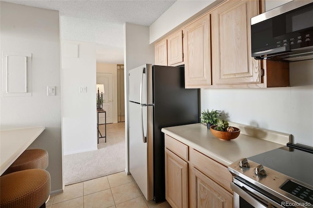 kitchen with light brown cabinets, electric panel, light countertops, appliances with stainless steel finishes, and a textured ceiling