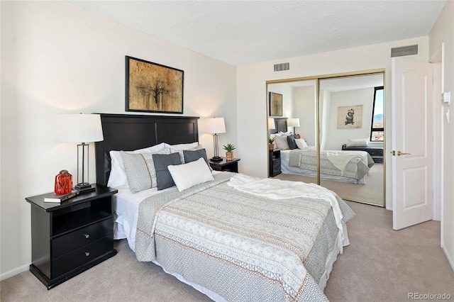 bedroom with light carpet, visible vents, a textured ceiling, and a closet