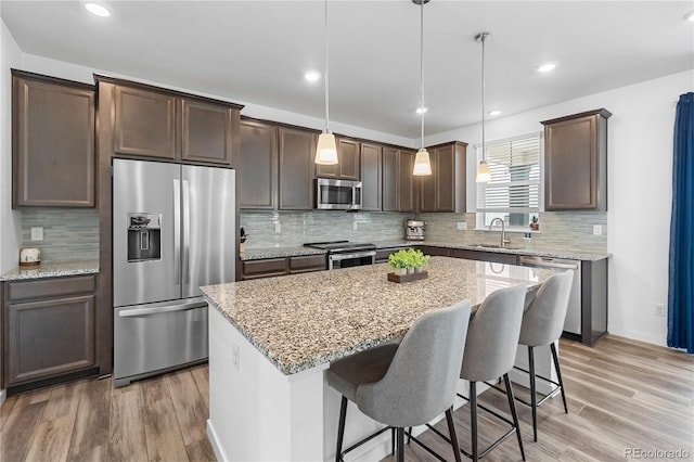 1168 Elbridge Dr, Elizabeth, CO 80107 - kitchen featuring stainless steel appliances, dark brown cabinets, a kitchen island, a breakfast bar, and light stone countertops