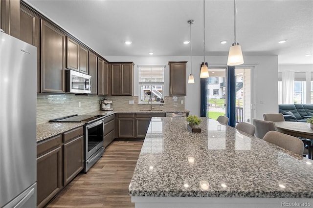 1168 Elbridge Dr, Elizabeth, CO 80107 - kitchen featuring stainless steel appliances, a kitchen island, a sink, stone counters, and dark brown cabinets