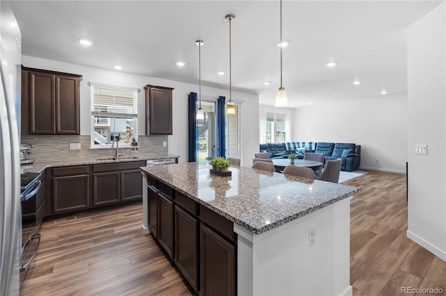 1168 Elbridge Dr, Elizabeth, CO 80107 - kitchen featuring decorative backsplash, a kitchen island, a sink, wood finished floors, and dark brown cabinets