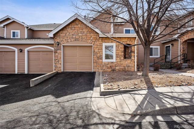 townhome / multi-family property featuring aphalt driveway and an attached garage