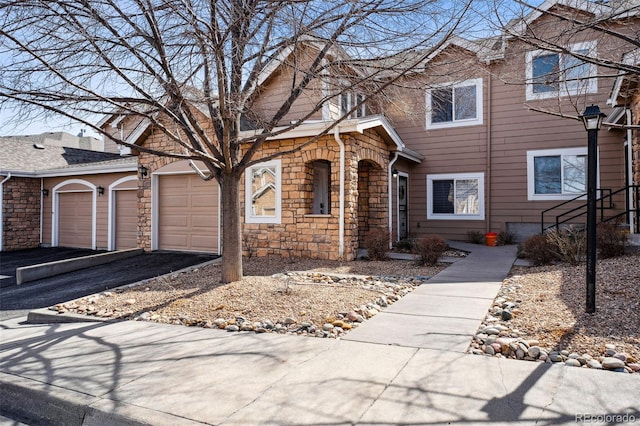 view of property with stone siding, driveway, and a garage