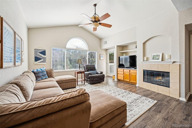 living area with visible vents, built in features, a tile fireplace, dark wood-style floors, and a ceiling fan