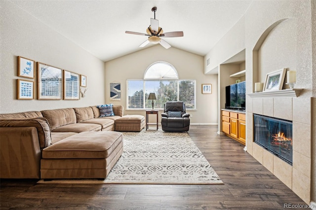 living area featuring built in shelves, dark wood-type flooring, ceiling fan, lofted ceiling, and a tile fireplace