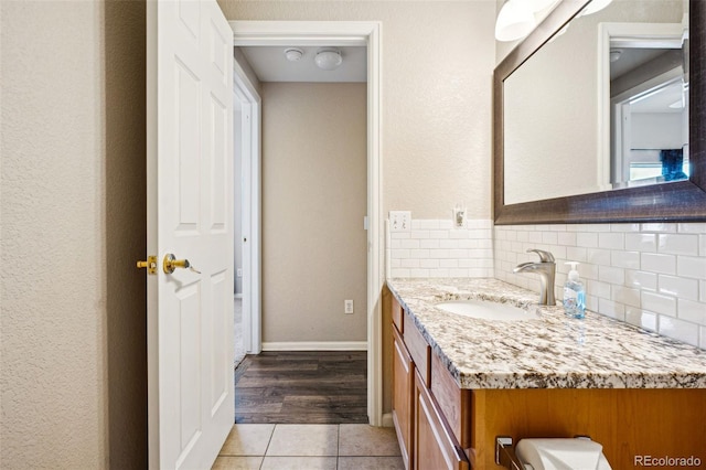 bathroom featuring vanity, tile patterned floors, baseboards, and backsplash