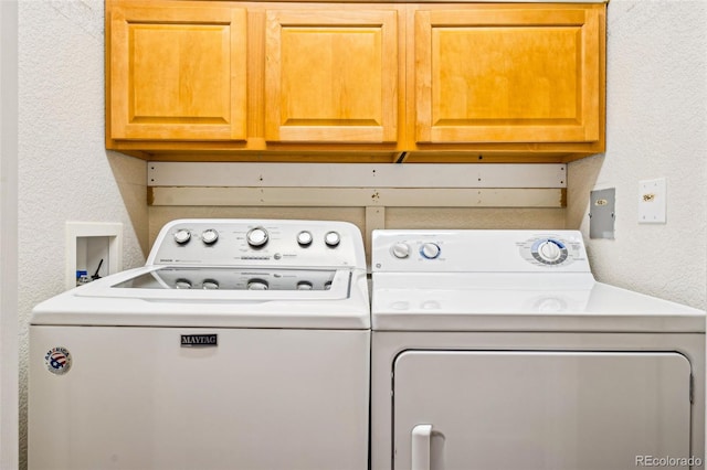 laundry room with cabinet space, a textured wall, and separate washer and dryer