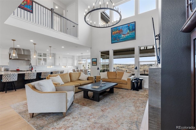 living room featuring an inviting chandelier, a high ceiling, light wood finished floors, and recessed lighting