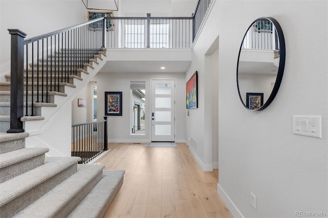 entrance foyer featuring baseboards, stairs, a high ceiling, and wood finished floors
