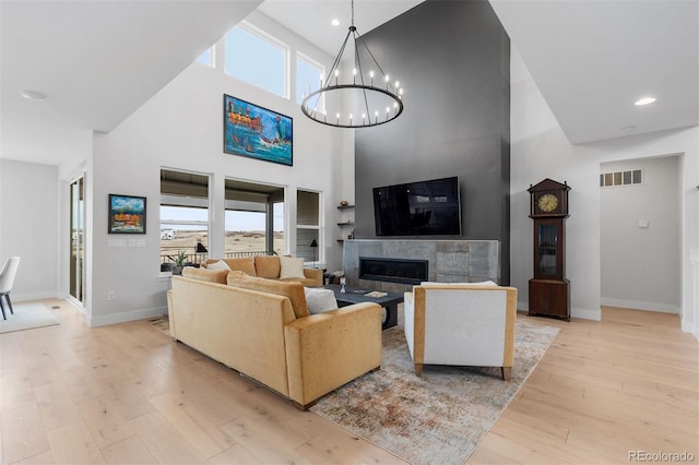 living area featuring a towering ceiling, a wealth of natural light, light wood-type flooring, and visible vents