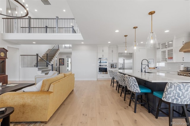 living room featuring recessed lighting, light wood-type flooring, stairs, a chandelier, and baseboards