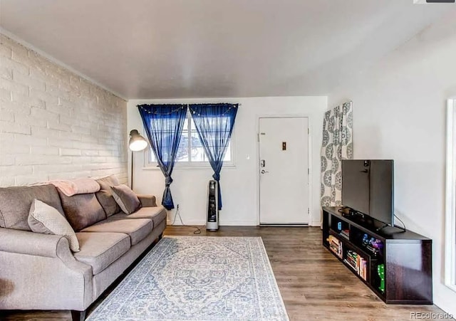 living room featuring brick wall and wood finished floors