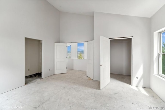 unfurnished bedroom featuring a high ceiling and multiple windows