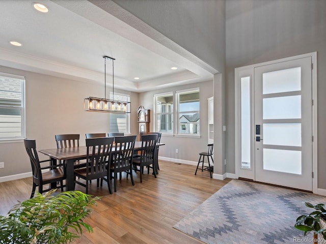 dining space with light hardwood / wood-style floors and a tray ceiling