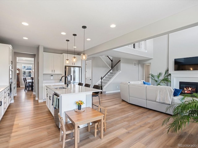 kitchen featuring white cabinetry, sink, decorative light fixtures, a center island with sink, and appliances with stainless steel finishes