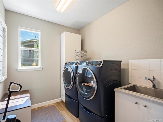 laundry area featuring cabinets, sink, light hardwood / wood-style floors, and washing machine and clothes dryer