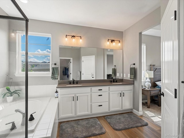 bathroom featuring hardwood / wood-style floors, vanity, and tiled tub